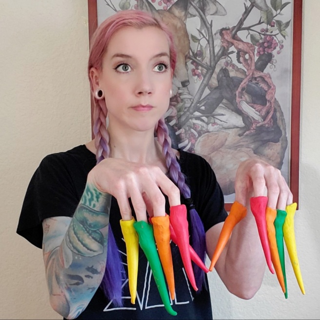 I showcase, with a limp wrist, all ten of my fingers fingers tipped with colourful modelling clay icicles. My hair is a pink to purple gradient, done in double braids.